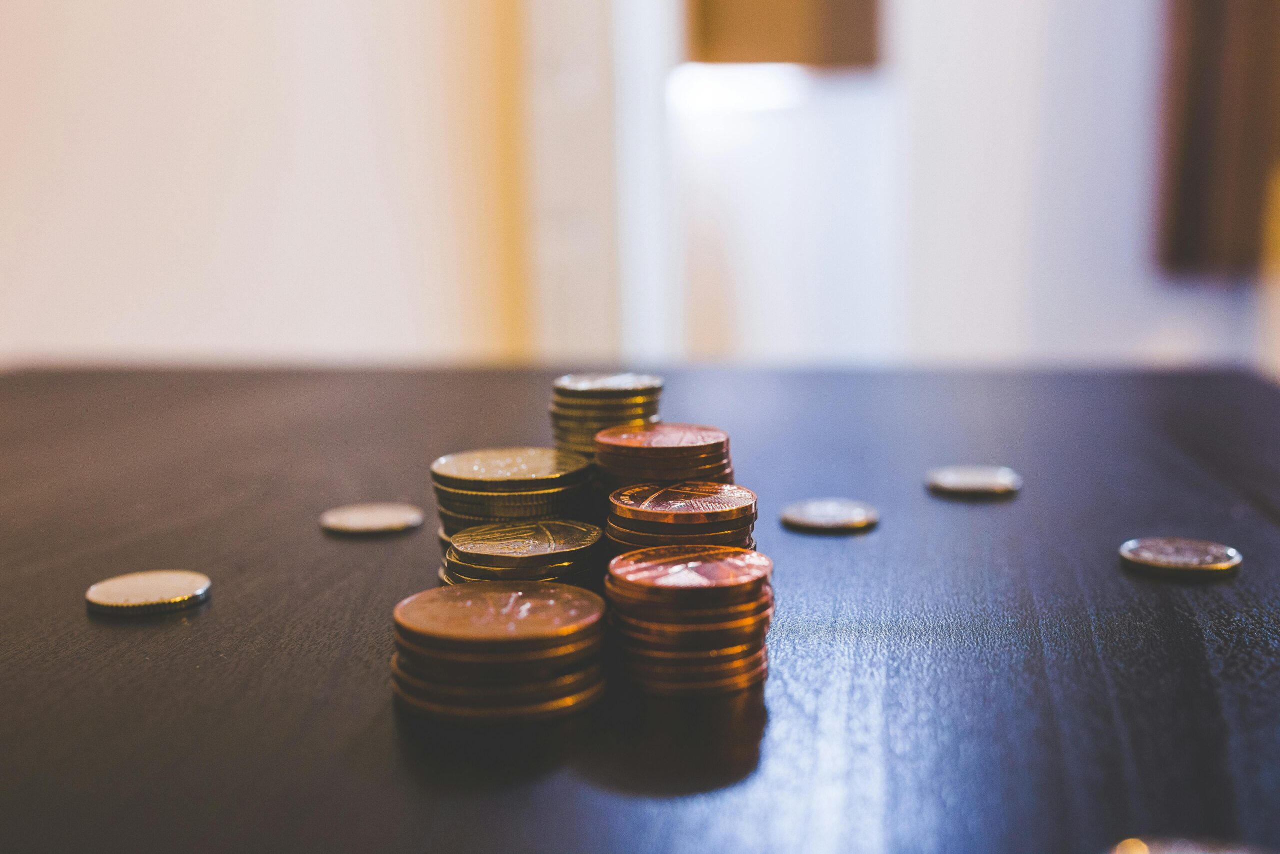 Academics Close-up of various coins stacked on a dark table indoors.