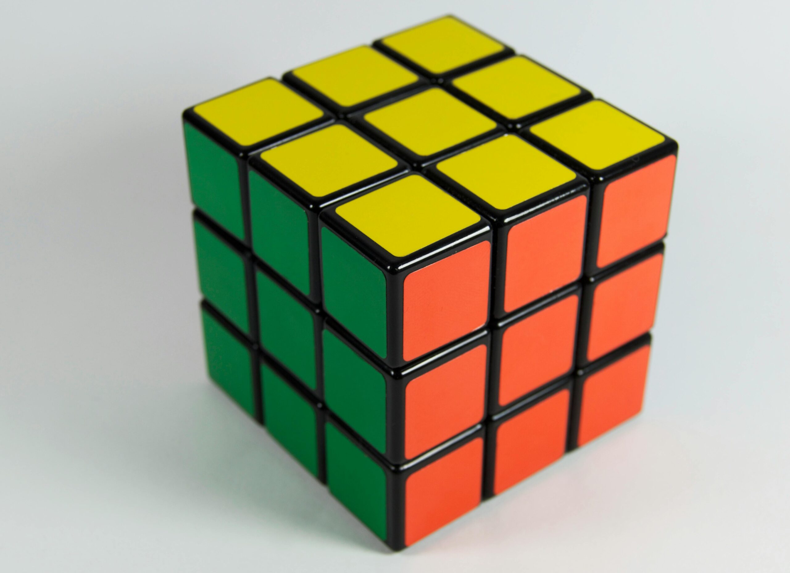 Academics A solved Rubik's Cube displaying red, yellow, and green colors on a white backdrop. Perfect for puzzle enthusiasts.